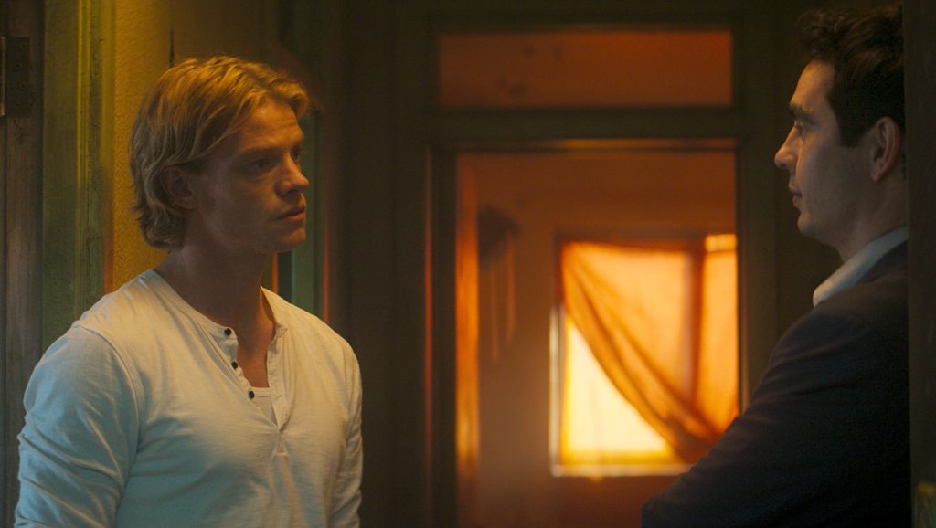 Tom Rhys Harries as Matt Hagen speaks to another man in a doorway in Clayface.